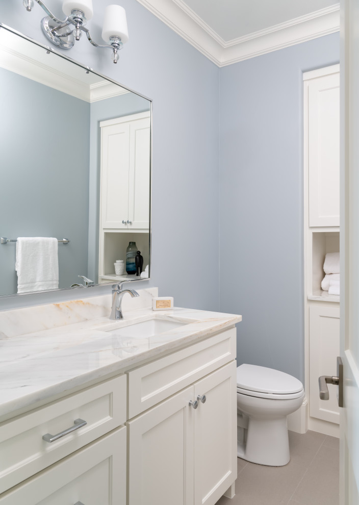 Inspiration for a mid-sized transitional white tile and porcelain tile porcelain tile, white floor and single-sink bathroom remodel with shaker cabinets, white cabinets, a one-piece toilet, blue walls, an undermount sink, marble countertops, a hinged shower door, white countertops and a built-in vanity