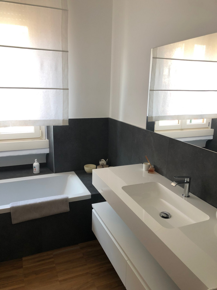 Photo of a medium sized modern cloakroom in Milan with flat-panel cabinets, white cabinets, black tiles, white walls, dark hardwood flooring, a trough sink, brown floors, white worktops and a floating vanity unit.