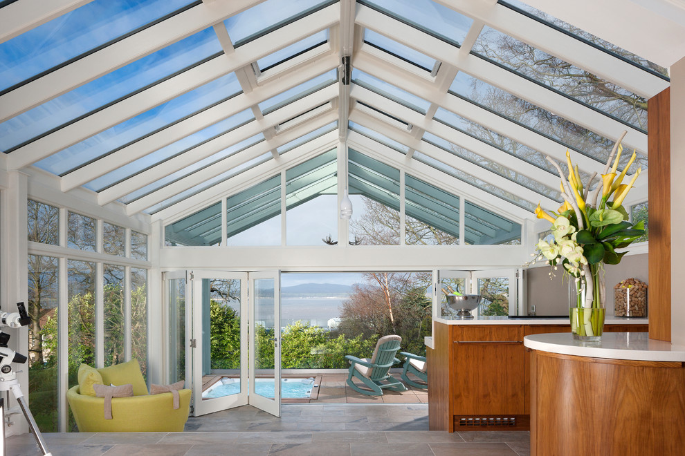 This is an example of a large modern sunroom in Glasgow with travertine floors, a glass ceiling and grey floor.