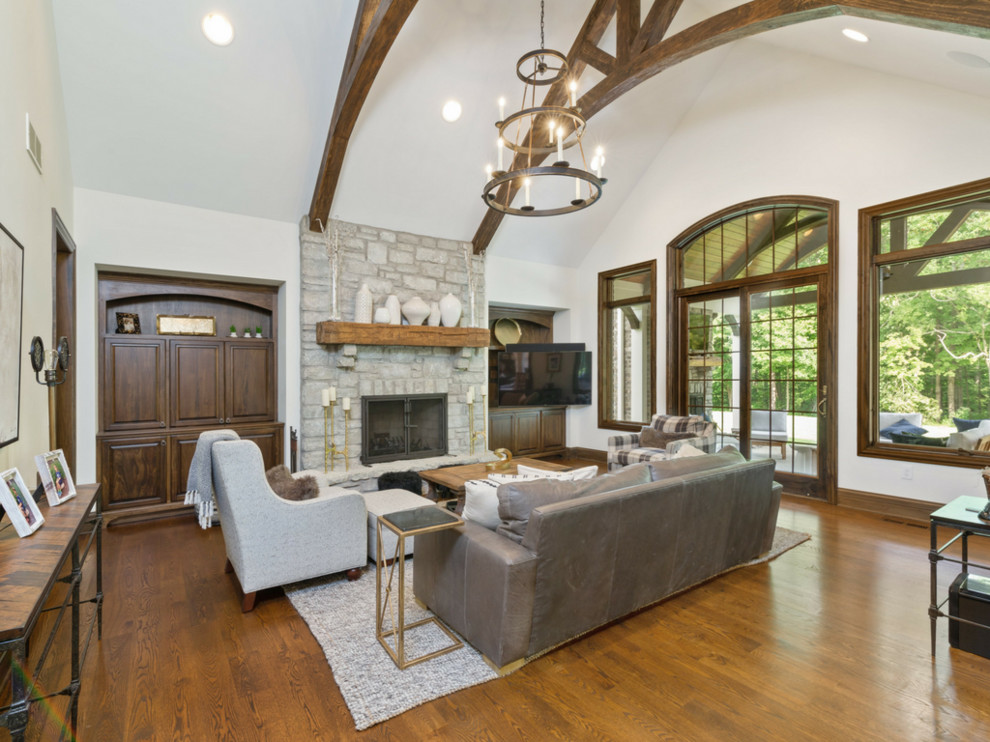 Large transitional open concept family room in Cincinnati with beige walls, medium hardwood floors, a standard fireplace, a stone fireplace surround, a built-in media wall and brown floor.