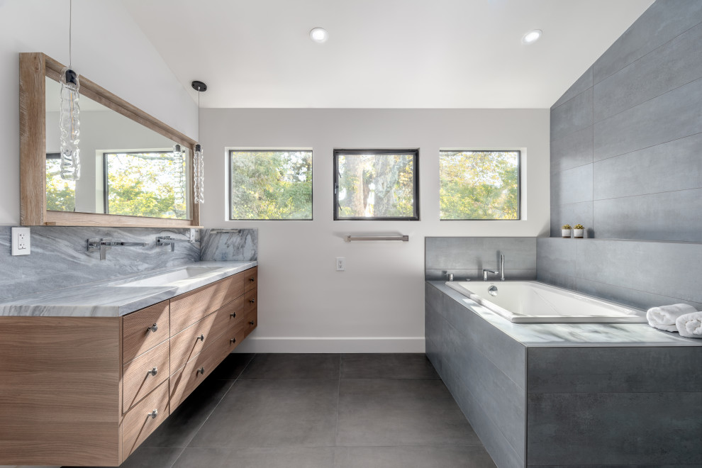 Drop-in bathtub - contemporary master gray tile concrete floor, gray floor and double-sink drop-in bathtub idea in San Francisco with flat-panel cabinets, medium tone wood cabinets, white walls, an undermount sink, marble countertops, gray countertops and a floating vanity