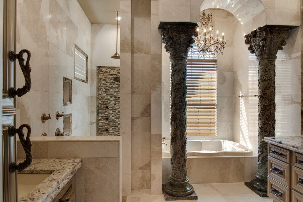 This is an example of a mid-sized mediterranean master bathroom in Atlanta with raised-panel cabinets, dark wood cabinets, a drop-in tub, beige tile, limestone, beige walls, limestone floors, granite benchtops, beige floor and brown benchtops.