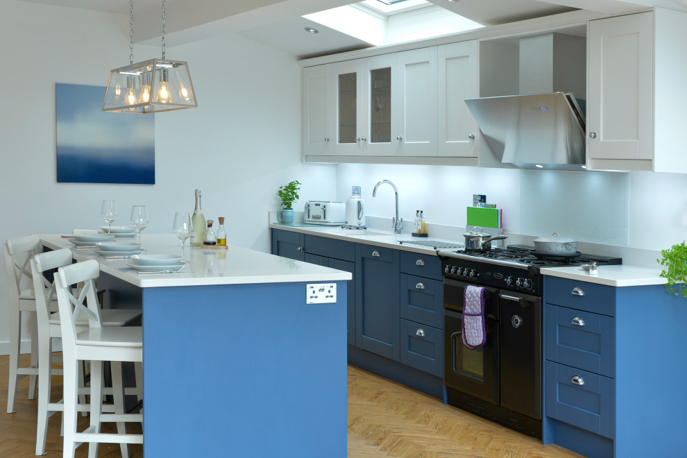 Imagen de cocina costera abierta con puertas de armario azules, encimera de cuarcita, una isla y encimeras blancas