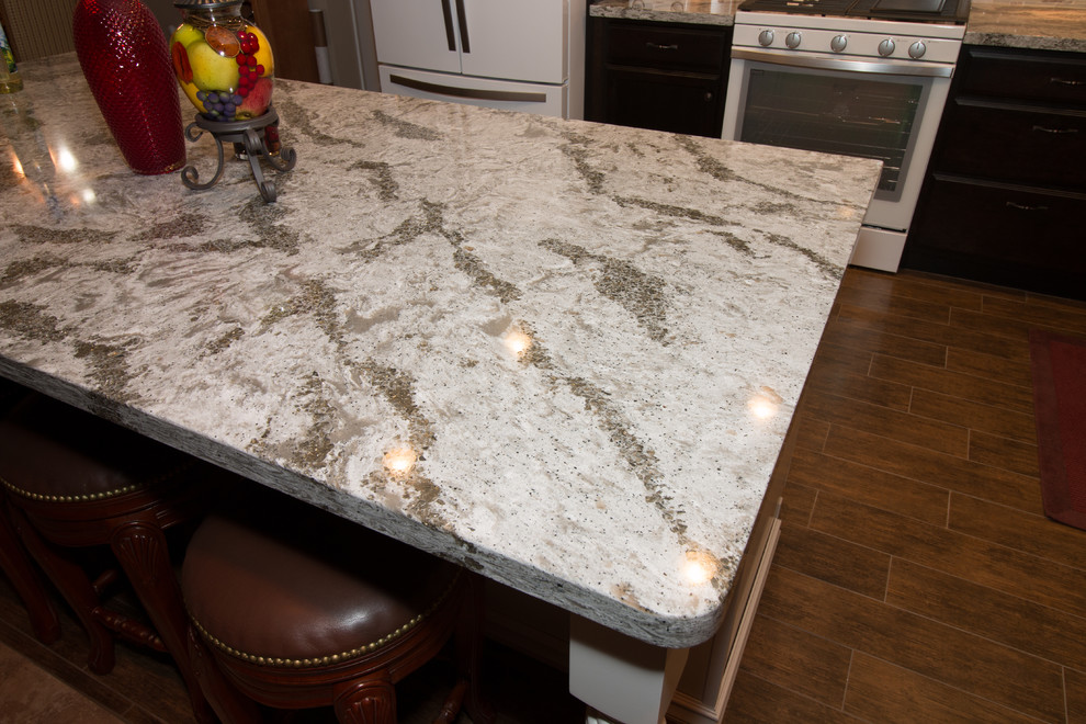 Mid-sized transitional l-shaped porcelain tile open concept kitchen photo with an undermount sink, flat-panel cabinets, dark wood cabinets, quartz countertops, beige backsplash, glass sheet backsplash, white appliances and an island