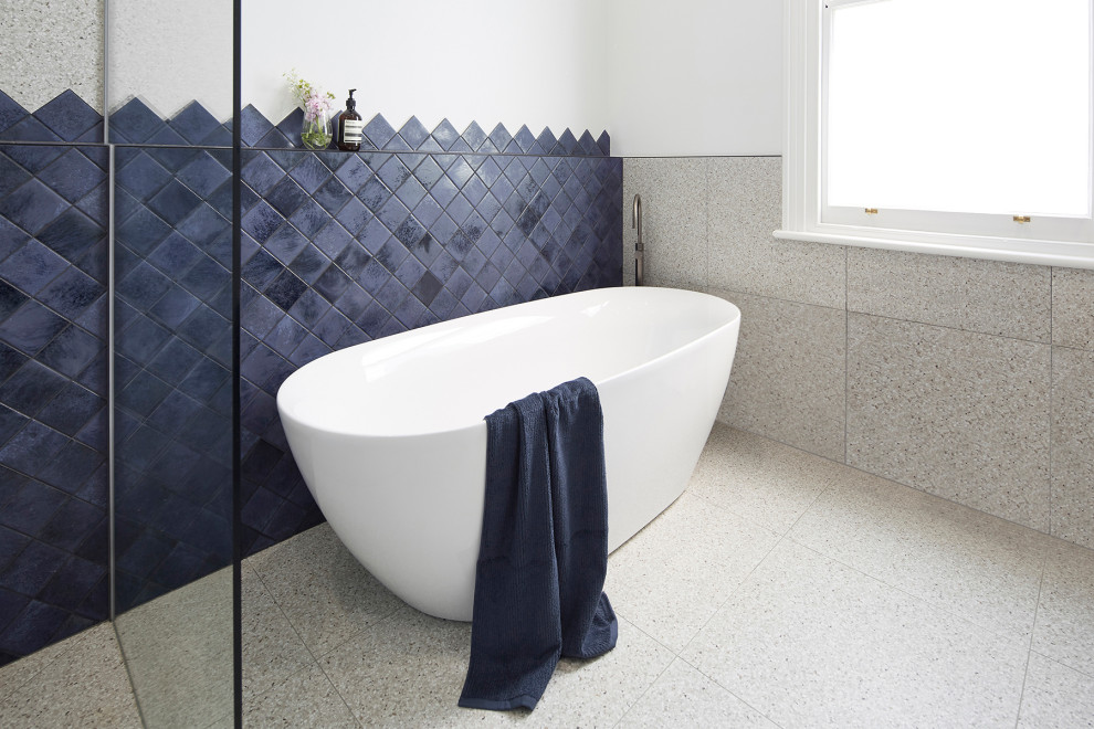 Inspiration for a large modern kids bathroom in Melbourne with flat-panel cabinets, blue cabinets, a freestanding tub, an open shower, a wall-mount toilet, gray tile, multi-coloured walls, terrazzo floors, a vessel sink, engineered quartz benchtops, multi-coloured floor, an open shower and white benchtops.