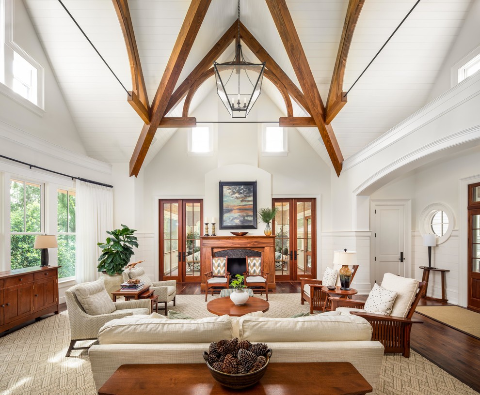 Inspiration for a large beach style open concept living room in Charleston with white walls, dark hardwood floors, a standard fireplace, a wood fireplace surround, no tv and brown floor.