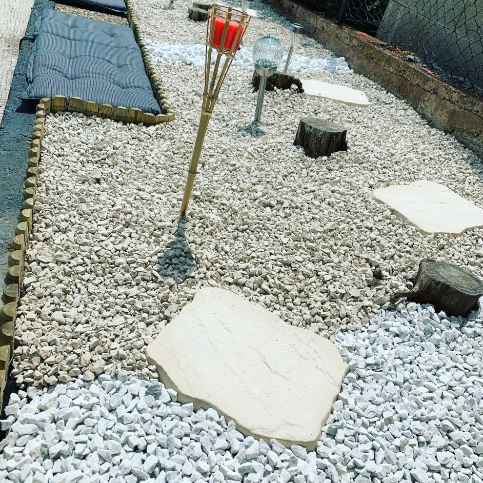 Diseño de jardín pequeño en patio trasero con roca decorativa y exposición total al sol