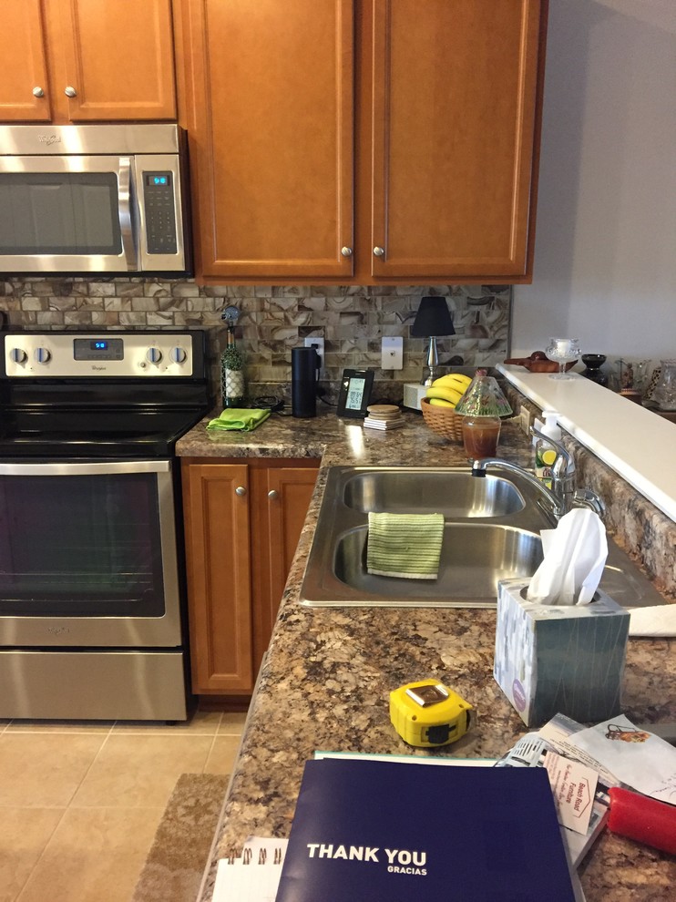 Example of a mid-sized transitional l-shaped vinyl floor and brown floor eat-in kitchen design in Wilmington with an undermount sink, gray backsplash, glass tile backsplash and stainless steel appliances