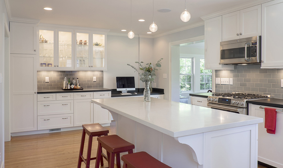 Inspiration for a mid-sized traditional l-shaped eat-in kitchen in Louisville with an undermount sink, shaker cabinets, white cabinets, concrete benchtops, grey splashback, ceramic splashback, stainless steel appliances, medium hardwood floors and with island.