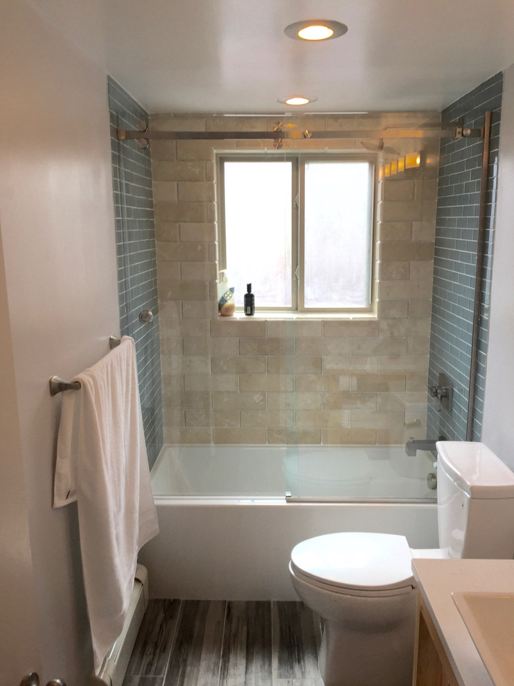 Mid-sized transitional 3/4 bathroom in Orange County with open cabinets, light wood cabinets, an alcove tub, a shower/bathtub combo, a two-piece toilet, blue tile, glass tile, white walls, dark hardwood floors, a drop-in sink, solid surface benchtops, brown floor and a sliding shower screen.