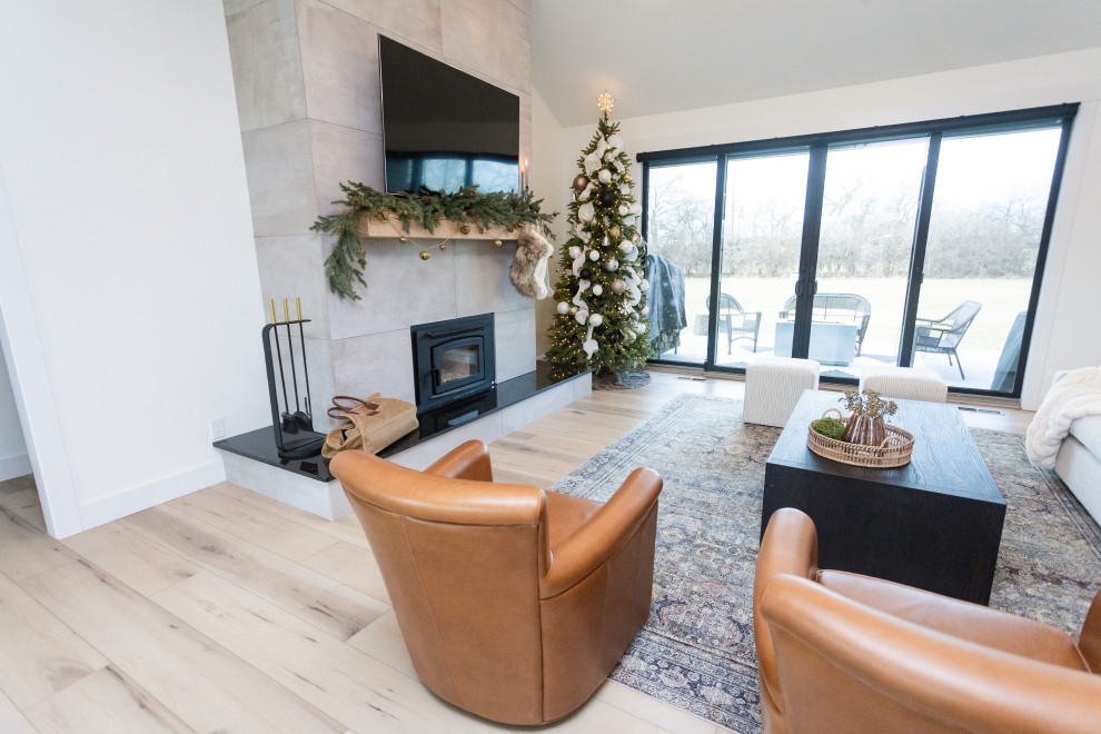 Mid-sized midcentury open concept living room in Cincinnati with a home bar, white walls, vinyl floors, a standard fireplace, a tile fireplace surround, a wall-mounted tv, beige floor and vaulted.