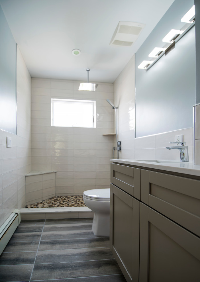 Inspiration for a mid-sized contemporary bathroom in New York with shaker cabinets, grey cabinets, an alcove shower, a two-piece toilet, white tile, ceramic tile, white walls, ceramic floors, an undermount sink, engineered quartz benchtops, grey floor and a hinged shower door.