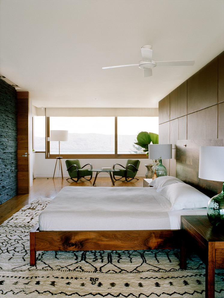 This is an example of a mid-sized beach style master bedroom in Sydney with multi-coloured walls and medium hardwood floors.