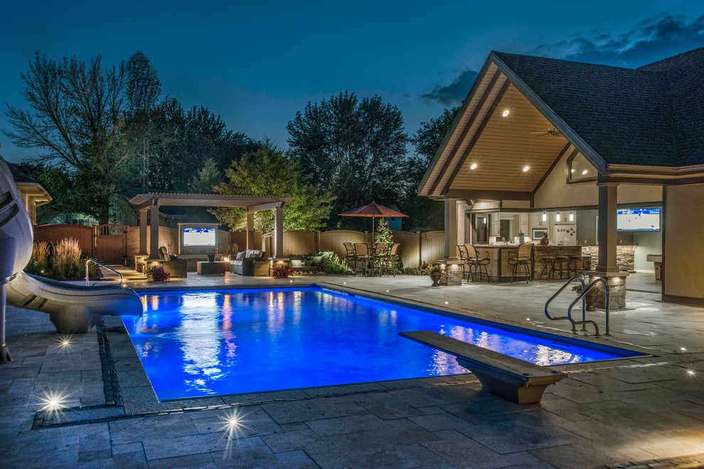 This is an example of a mid-sized traditional backyard rectangular lap pool in Chicago with a pool house and natural stone pavers.