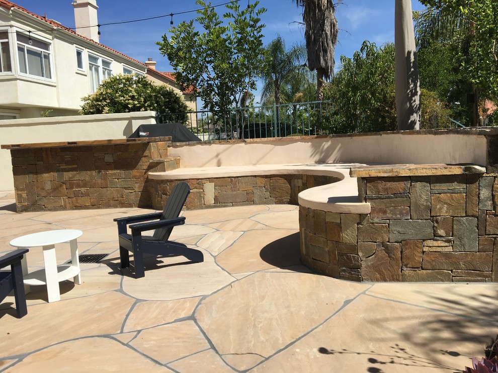 Photo of a mid-sized country backyard patio in Los Angeles with an outdoor kitchen, natural stone pavers and no cover.