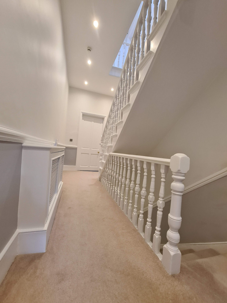 This is an example of a large traditional hallway in London with beige walls, carpet, beige floor and coffered.