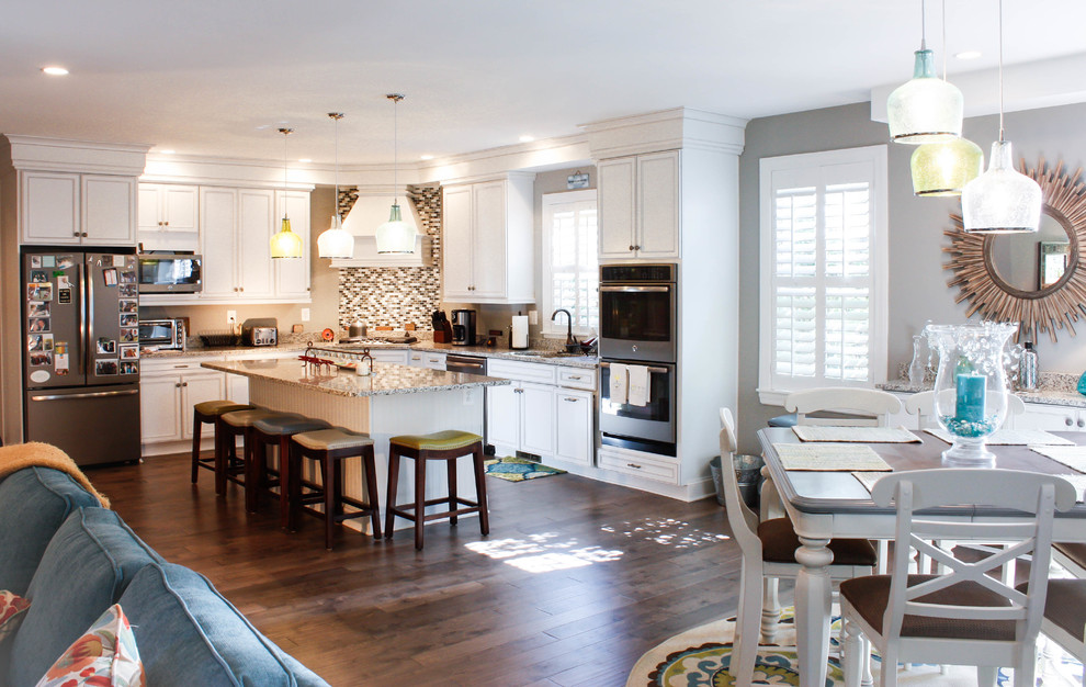 Inspiration for a mid-sized transitional l-shaped medium tone wood floor open concept kitchen remodel in Baltimore with white cabinets, granite countertops, multicolored backsplash, matchstick tile backsplash, stainless steel appliances and an island