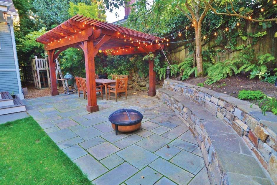 This is an example of a mid-sized traditional backyard patio in Seattle with natural stone pavers and a pergola.