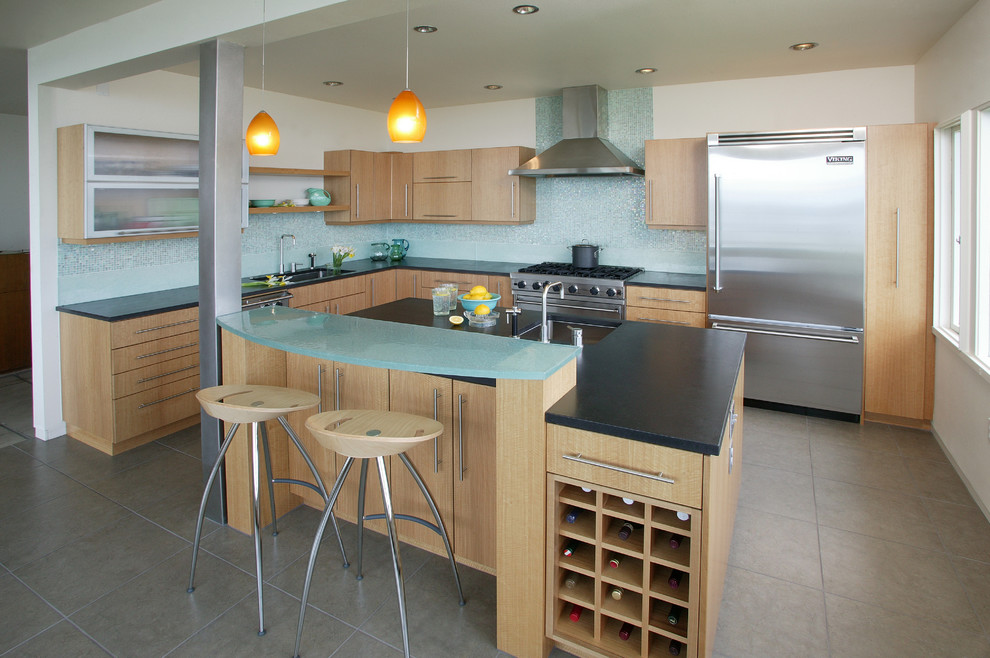 Photo of a contemporary l-shaped kitchen in Seattle with stainless steel appliances, glass benchtops, flat-panel cabinets, light wood cabinets, blue splashback and turquoise benchtop.