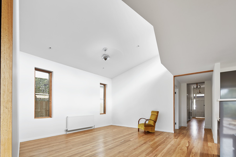 Mid-sized contemporary loft-style family room with white walls, medium hardwood floors and no tv.