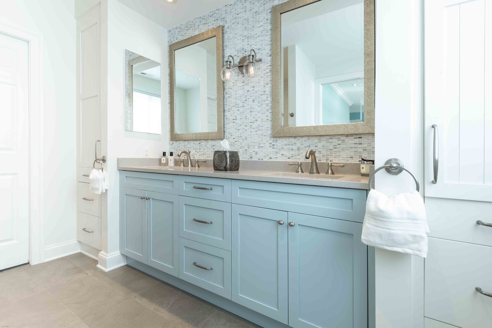 Design ideas for a mid-sized beach style master bathroom in DC Metro with beaded inset cabinets, blue cabinets, an alcove shower, a two-piece toilet, multi-coloured tile, matchstick tile, white walls, limestone floors, an undermount sink, limestone benchtops, grey floor, a hinged shower door and grey benchtops.