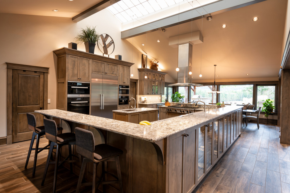 Example of a huge transitional u-shaped ceramic tile and brown floor open concept kitchen design in Seattle with a single-bowl sink, shaker cabinets, dark wood cabinets, quartz countertops, stainless steel appliances, two islands and multicolored countertops