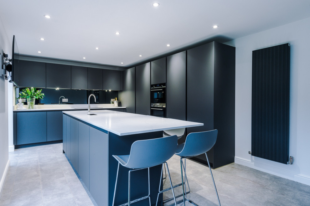 Inspiration for a mid-sized contemporary kitchen in Manchester with an undermount sink, flat-panel cabinets, grey cabinets, quartzite benchtops, grey splashback, glass sheet splashback, stainless steel appliances, with island and white benchtop.