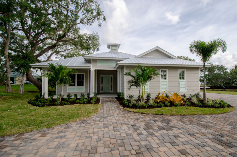 Mid-sized tropical one-storey grey house exterior in Miami with vinyl siding, a hip roof and a metal roof.