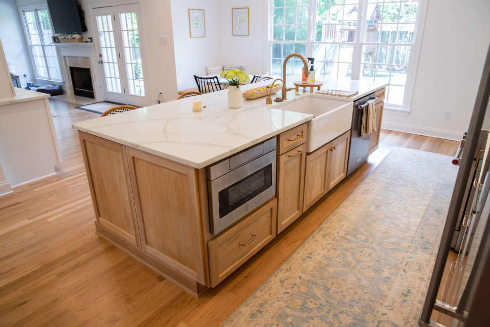 Example of a large minimalist l-shaped medium tone wood floor and brown floor enclosed kitchen design with recessed-panel cabinets, white cabinets, white backsplash, stainless steel appliances and an island