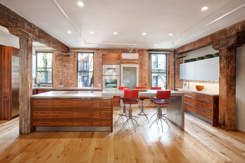 Large industrial eat-in kitchen in New York with an undermount sink, flat-panel cabinets, medium wood cabinets, concrete benchtops, red splashback, stainless steel appliances, medium hardwood floors and with island.
