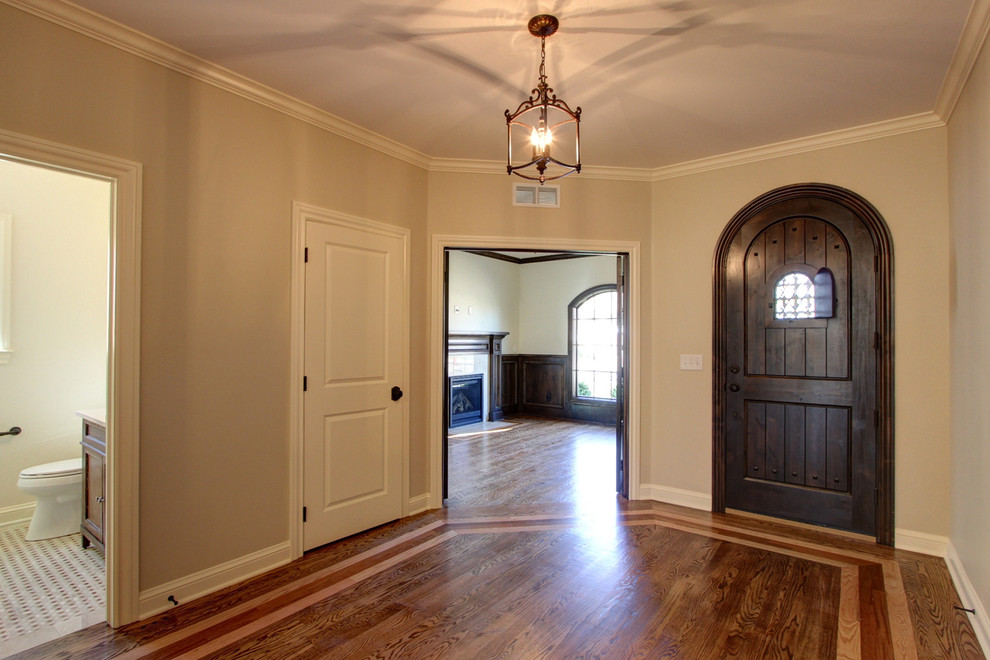 This is an example of a mid-sized mediterranean foyer in Denver with white walls, medium hardwood floors, a single front door and a dark wood front door.