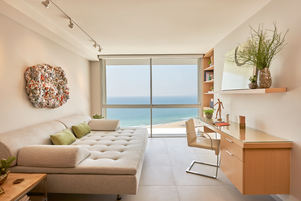 Photo of a beach style home studio in Los Angeles with beige walls, a built-in desk and beige floor.