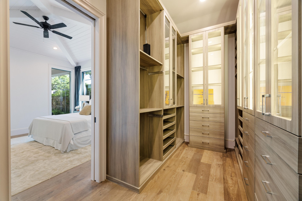 Photo of an expansive classic gender neutral walk-in wardrobe in Houston with flat-panel cabinets, light wood cabinets, medium hardwood flooring and brown floors.