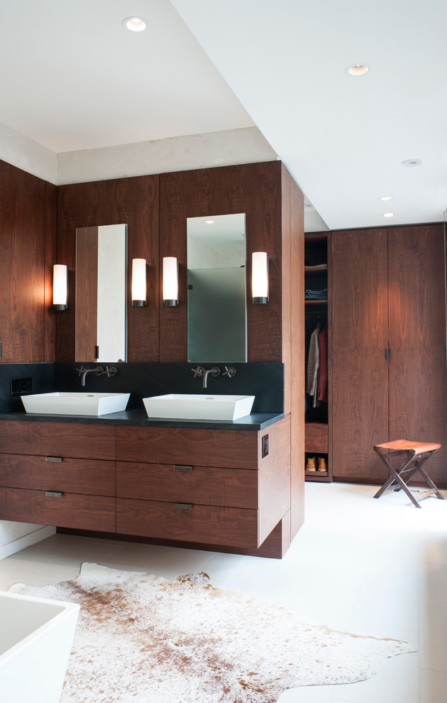 Photo of a mid-sized contemporary master bathroom in DC Metro with a vessel sink, flat-panel cabinets, dark wood cabinets, soapstone benchtops, a freestanding tub, white tile, porcelain tile, white walls, porcelain floors and an open shower.