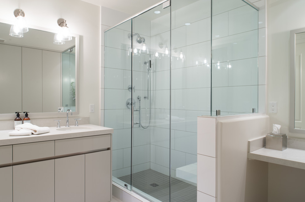 Photo of a large contemporary master bathroom in San Diego with flat-panel cabinets, grey cabinets, a corner shower, white tile, ceramic tile, white walls, ceramic floors, an undermount sink, engineered quartz benchtops, white floor and a hinged shower door.