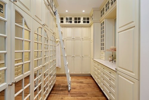 Large traditional women's walk-in wardrobe in Milwaukee with white cabinets and medium hardwood floors.