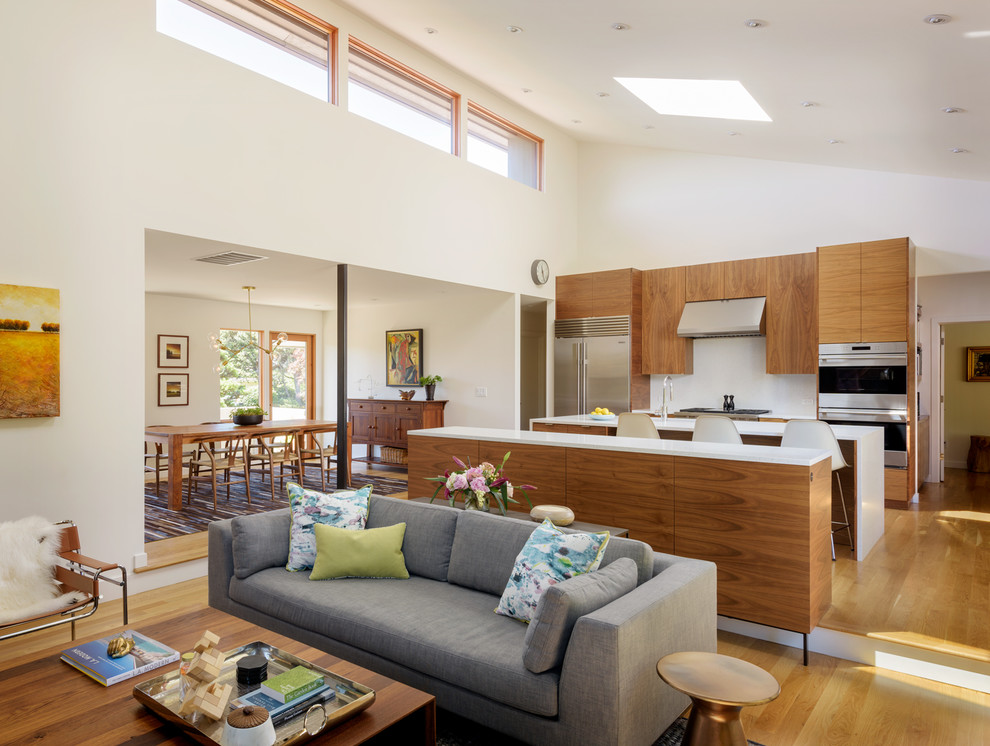 Mid-sized minimalist light wood floor open concept kitchen photo in Portland with flat-panel cabinets, medium tone wood cabinets, stainless steel appliances, an island and white countertops