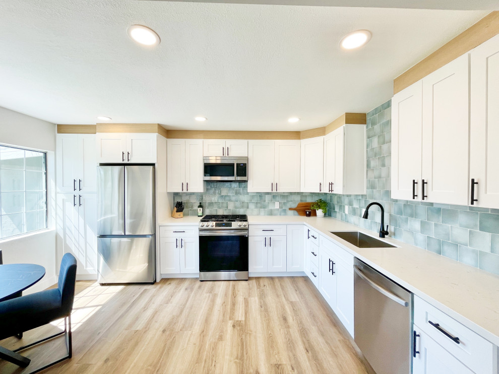 サンディエゴにある低価格の中くらいなカントリー風のおしゃれなキッチン (アンダーカウンターシンク、シェーカースタイル扉のキャビネット、白いキャビネット、クオーツストーンカウンター、緑のキッチンパネル、磁器タイルのキッチンパネル、シルバーの調理設備、クッションフロア、ベージュの床、白いキッチンカウンター) の写真