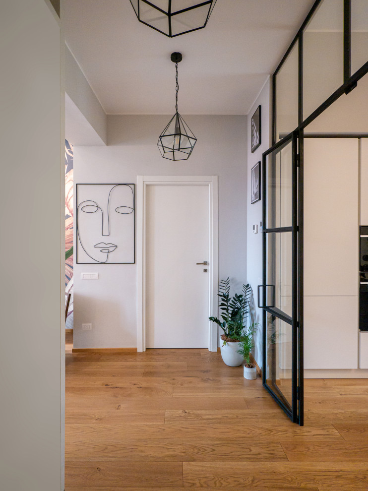 Foto på en stor funkis entré, med grå väggar, ljust trägolv, en enkeldörr och en vit dörr