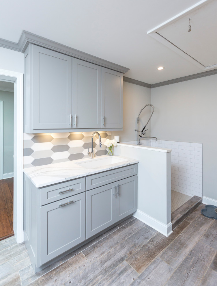 Inspiration for a small galley utility room in Cincinnati with an undermount sink, recessed-panel cabinets, grey cabinets, quartz benchtops, multi-coloured splashback, ceramic splashback, grey walls, porcelain floors, a side-by-side washer and dryer, grey floor and white benchtop.