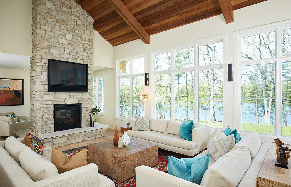 Photo of a country open concept family room with white walls, light hardwood floors, a two-sided fireplace, a metal fireplace surround, a wall-mounted tv and brown floor.
