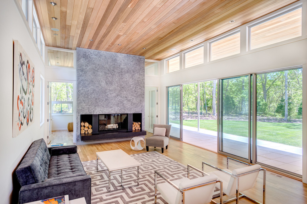 Photo of a large modern formal open concept living room in New York with white walls, light hardwood floors, a two-sided fireplace, a stone fireplace surround, no tv and beige floor.