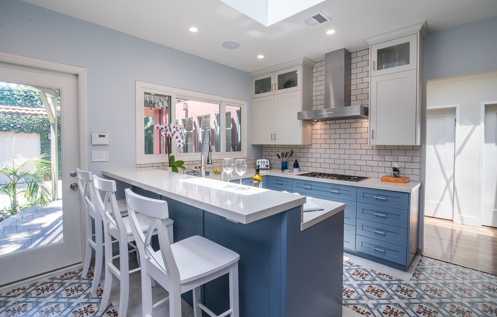 Design ideas for a mid-sized transitional u-shaped separate kitchen in Los Angeles with shaker cabinets, blue cabinets, white splashback, subway tile splashback, a peninsula, multi-coloured floor, white benchtop, an undermount sink, limestone benchtops, stainless steel appliances and ceramic floors.
