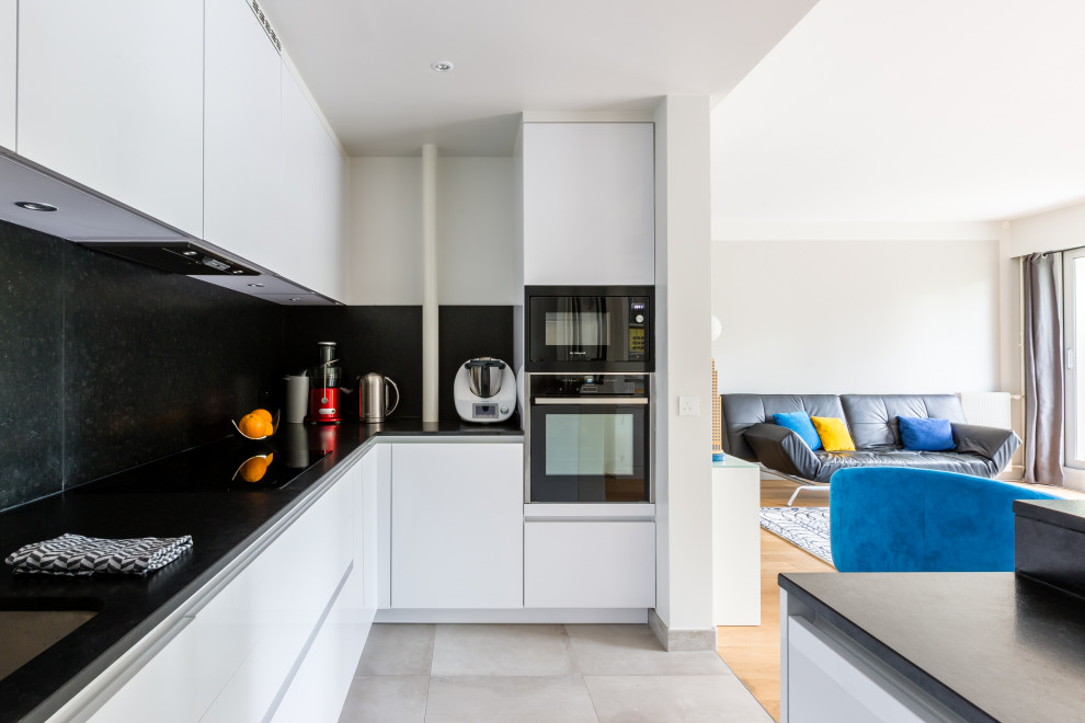 Inspiration for a contemporary u-shaped kitchen in Paris with an undermount sink, flat-panel cabinets, white cabinets, black splashback, black appliances, with island, grey floor and black benchtop.
