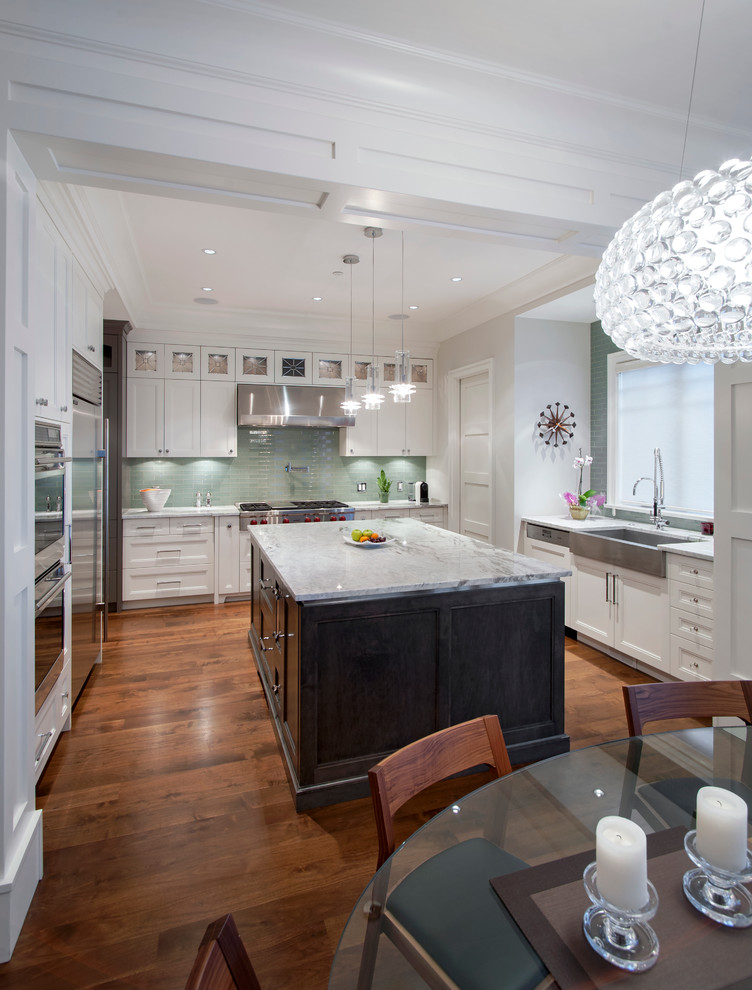Inspiration for a transitional u-shaped eat-in kitchen in Vancouver with a farmhouse sink, recessed-panel cabinets, granite benchtops, green splashback, stainless steel appliances, dark hardwood floors, with island, white cabinets and glass tile splashback.