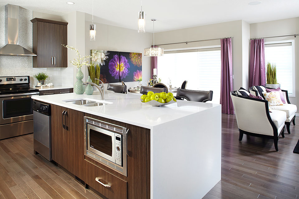 Moderne Wohnküche in L-Form mit Einbauwaschbecken, hellbraunen Holzschränken und Küchengeräten aus Edelstahl in Calgary