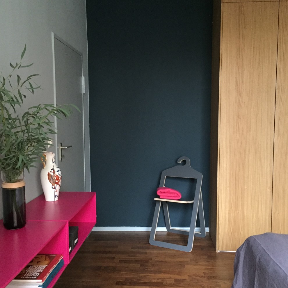 Photo of a mid-sized scandinavian master bedroom in Berlin with blue walls, dark hardwood floors, a standard fireplace, a plaster fireplace surround and brown floor.