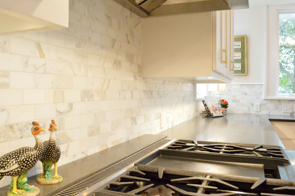 Example of a kitchen design in Austin with an undermount sink, shaker cabinets, white cabinets, quartz countertops, white backsplash, stone tile backsplash, stainless steel appliances and an island