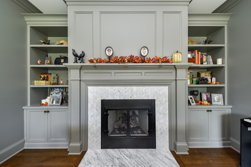 Inspiration for a large traditional home office in Chicago with a library, grey walls, medium hardwood floors, a standard fireplace, a tile fireplace surround, a freestanding desk, brown floor and coffered.