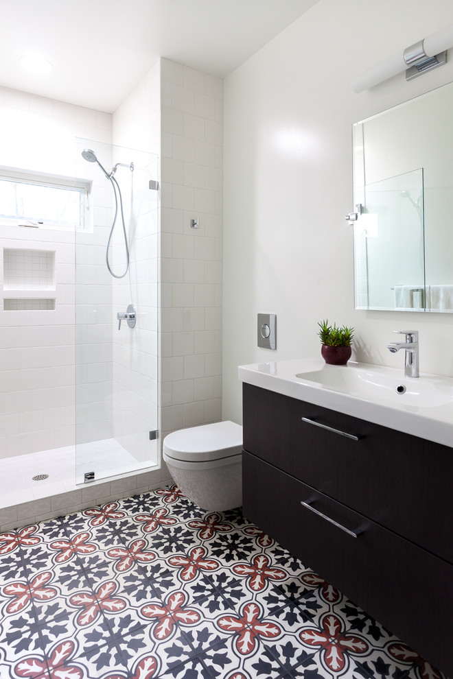 This is an example of a mid-sized contemporary bathroom in Sacramento with a wall-mount toilet, gray tile, cement tile, white walls, concrete floors and solid surface benchtops.